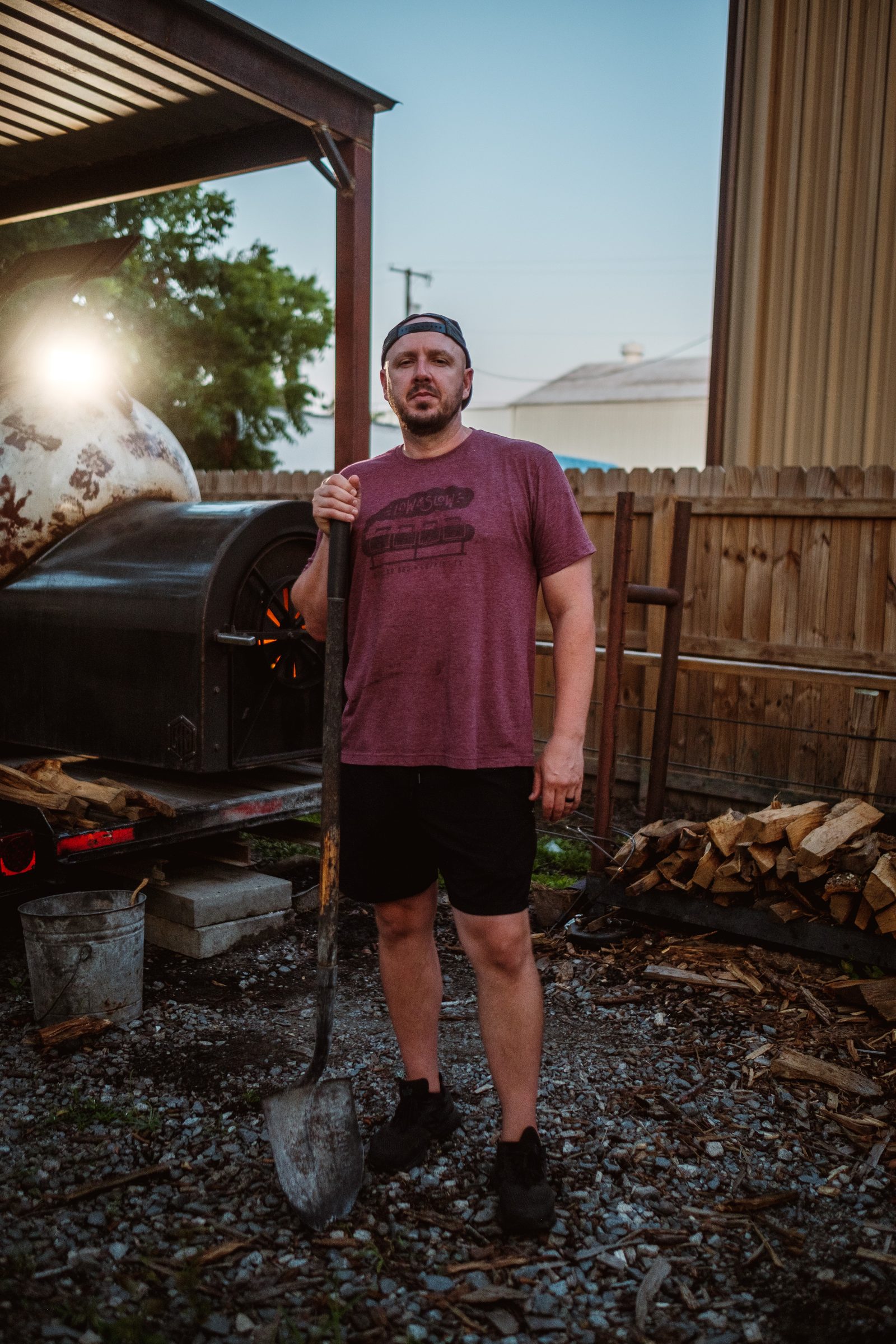 Jeremy standing with a shovel beside the smoker firebox
