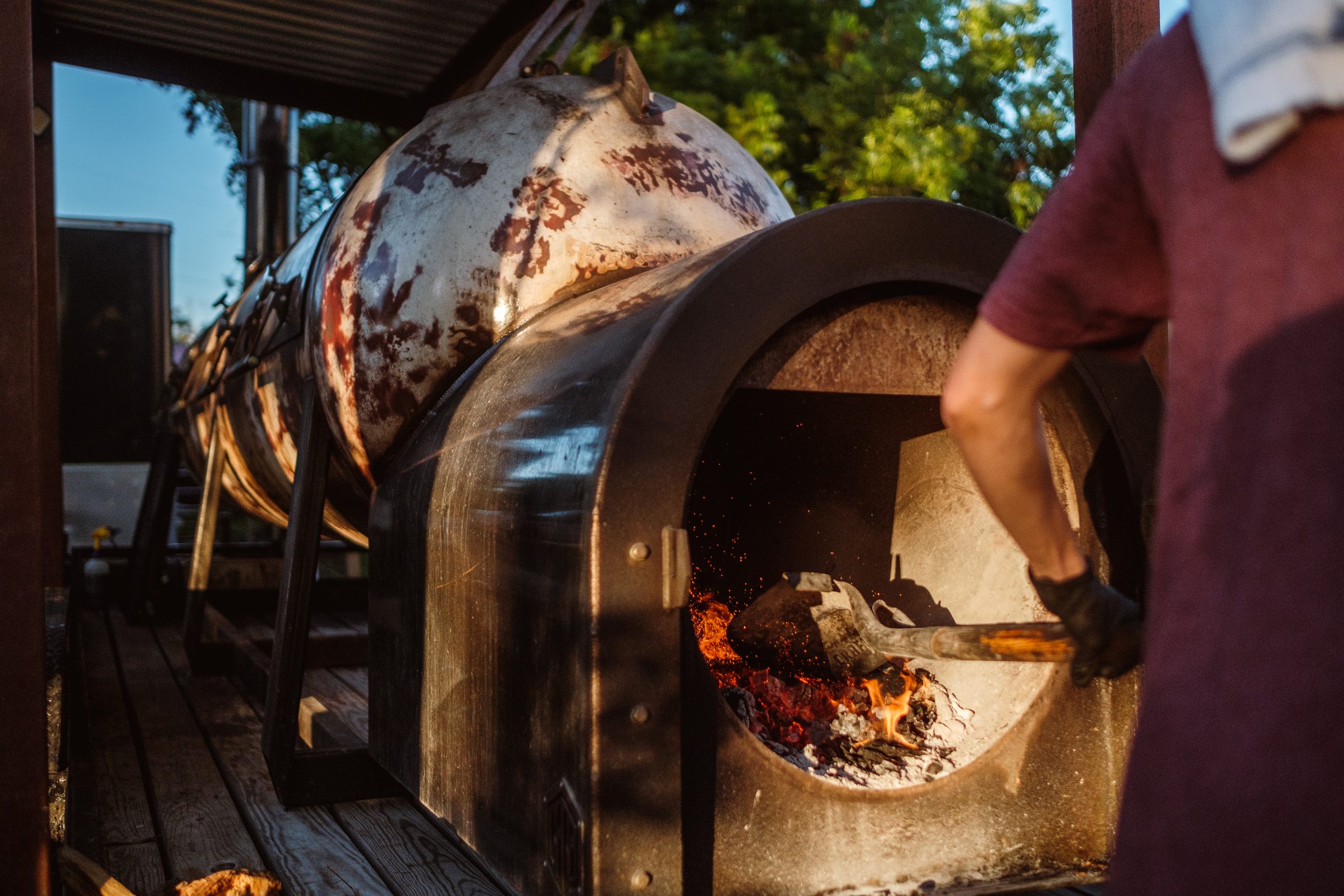 Shovel of coals going into a glowing firebox in golden light